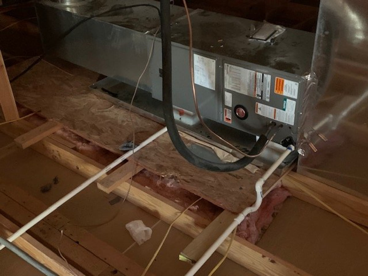 HVAC air handler and duct connections installed on an attic platform.